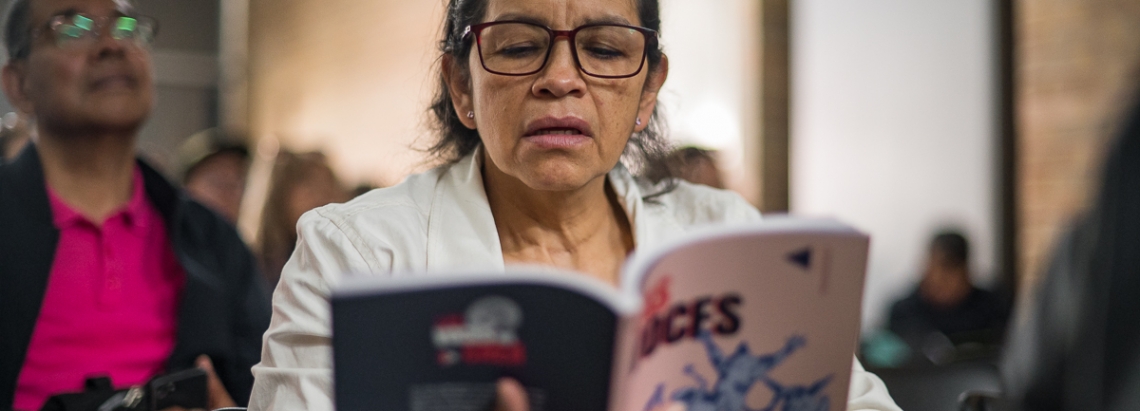 Durante un evento, una mujer lee un ejemplar del libro Las voces del Crea