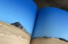 Libro abierto con imagen de playa en su interior. 