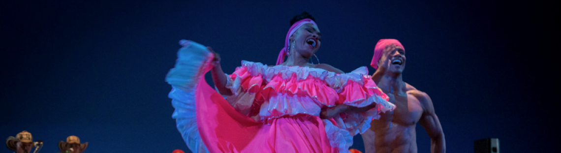 Bailarines danzando en el escenario con trajes coloridos