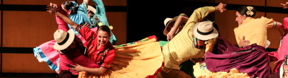 Personas de trajes coloridos y alegres bailando en un escenario