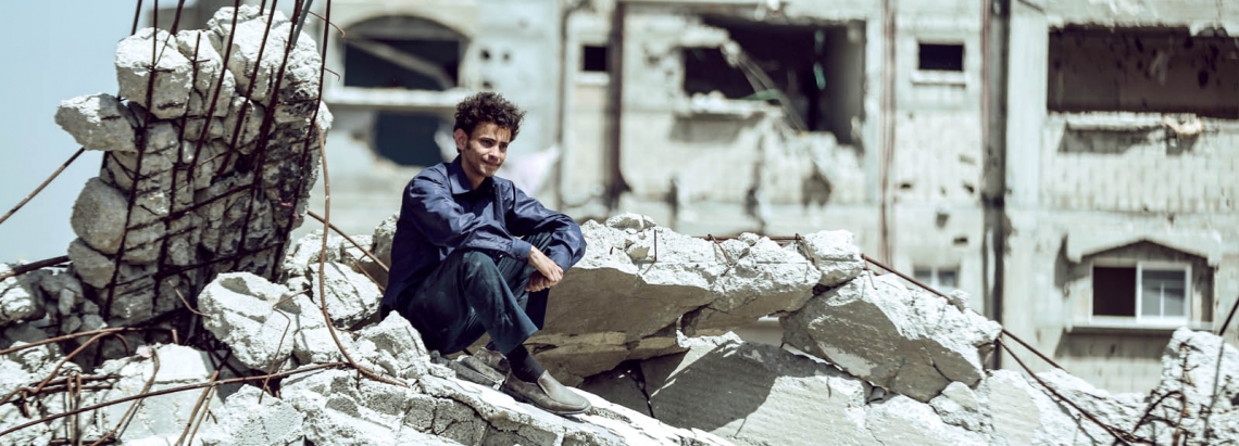 hombre sentado en escombros en Palestina