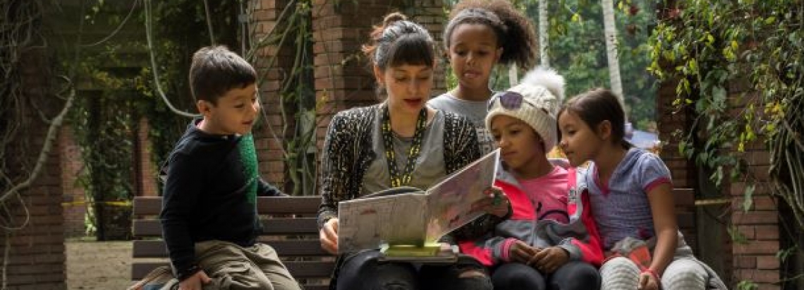 Mujer lee libro a niños