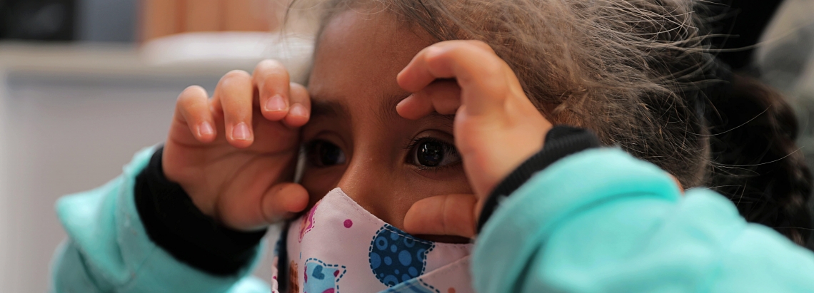 Niña jugando a los binoculares con sus manos.