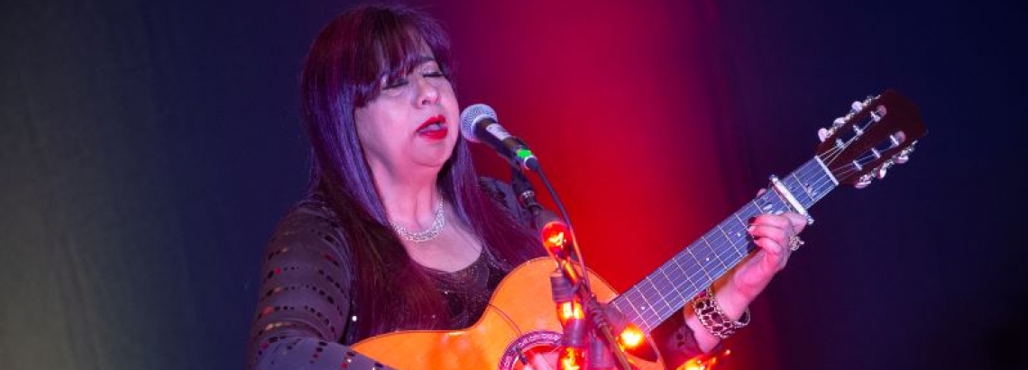 Mujer cantando en el escenario con guitarra en mano