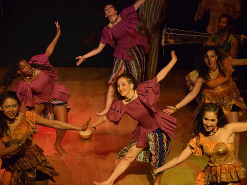 Bailarines danzando en el escenario con trajes coloridos
