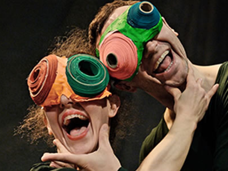 Dos actores con máscaras de ojos grandes en escena