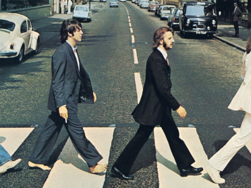 Integrantes de The Beatles caminando sobre la zebra en una calle. 