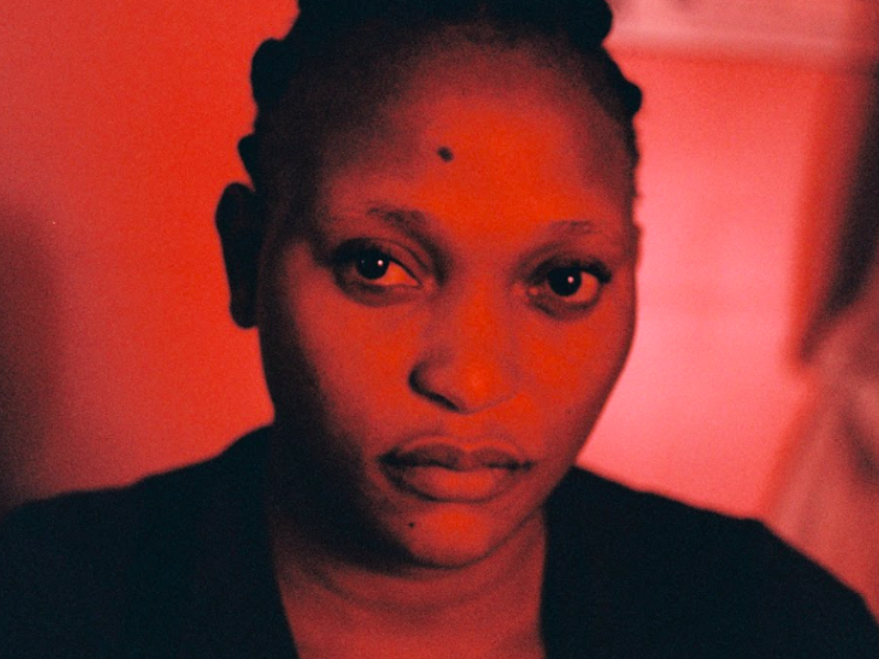 Mujer mirando de frente en un cuarto con luz roja 