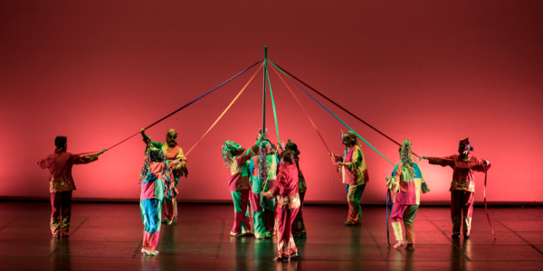 Grupo de bailarines con  lazos de colores entrelazados en el escenario