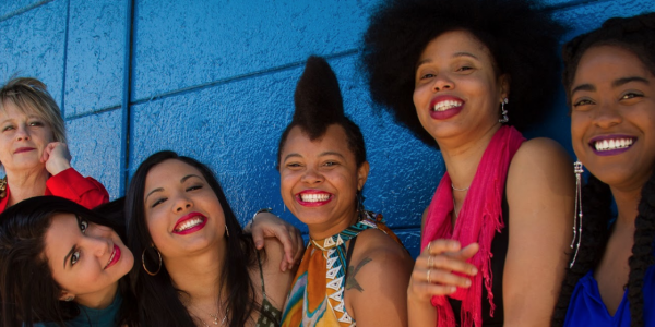 Mujeres sonriendo para la cámara sobre un fondo azul