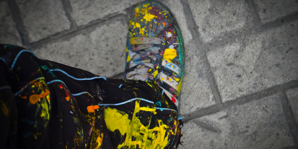 Zapato y pantalón de grafitero sobre baldosa pintados de muchos colores por pintura caída