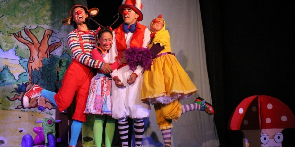 Actores adultos y niños vestidos de colores en un escenario