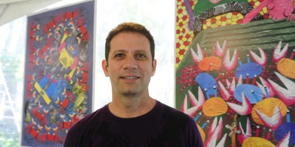 Roger Mello posando en frente de dos cuadros de colores