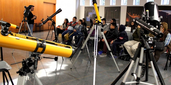 Personas participando en una charla con telescopios