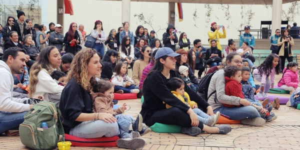 Personas con bebés sentados en el piso viendo presentación