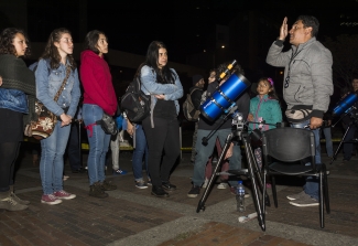 Personas  reunidas al rededor de un telescopio 