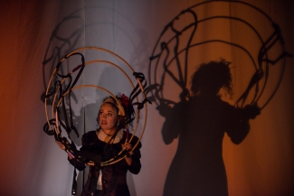 Actriz con circulos proyectando su sombra en la pared del escenario