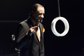 Hombre hablando frente a un círculo blanco que cuelga sobre el escenario
