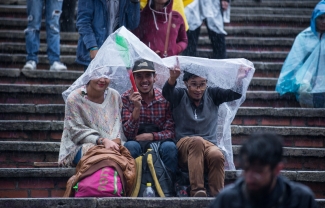 Grupo de amigos bajo un plástico, cubriéndose de la lluvia en las graderías de la Media Torta