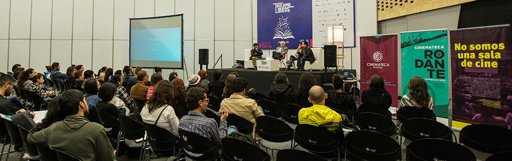 Grupo de personas en una sala con silletería y escenario