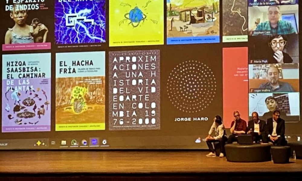En un escenario se proyecta una pantalla en el que un panel expone las publicaciones realizadas por la Línea ACT del idartes. El escenario hace parte de la programación de la vigesimo cuarta edición del Festival de la Imagen en Manizales.