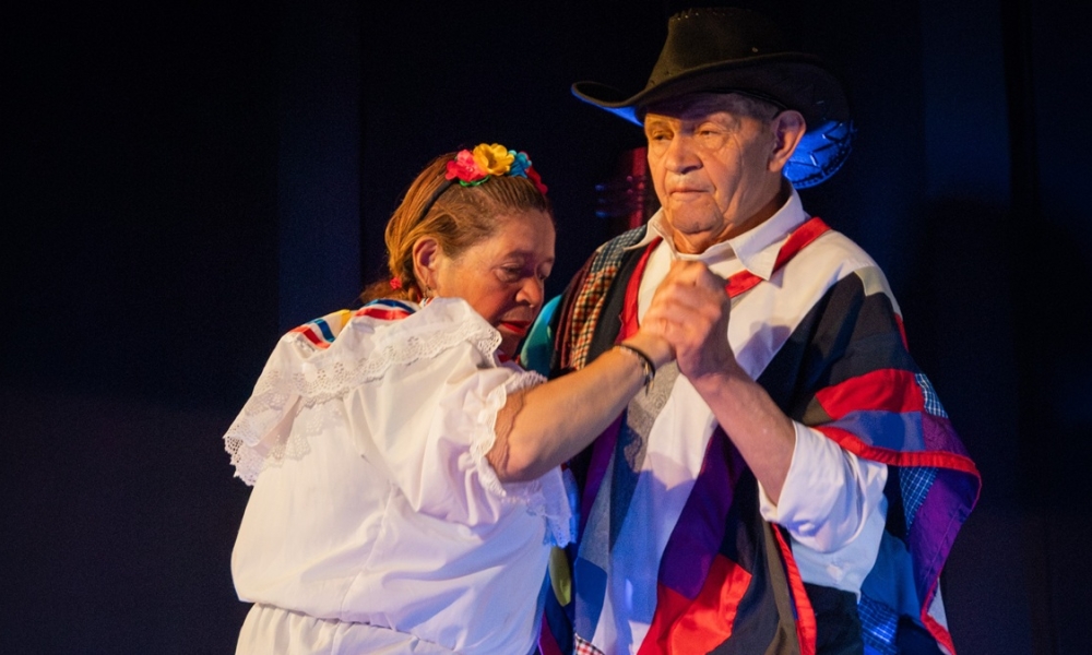 dos personas mayores bailan en un escenario