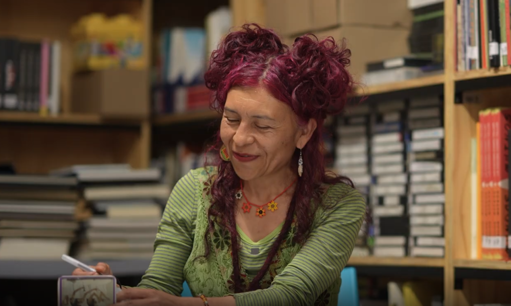 captura de pantalla del video de entrevista de la Escritora Liliana Moreno, quien se encuentra en una biblioteca escribiendo