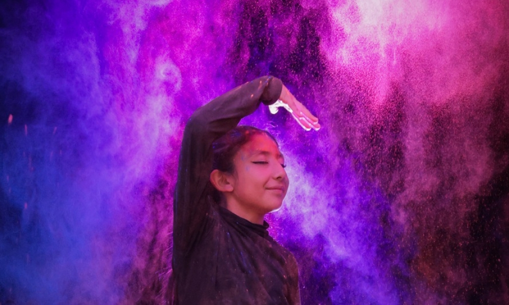 Una niña baila en medio de humo de colores
