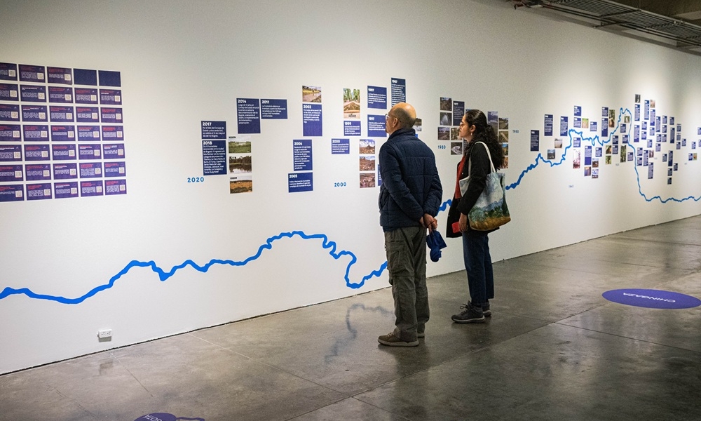 Un hombre y una mujer repasan la línea del tiempo colocada en la exposición de Ciudad de Agua