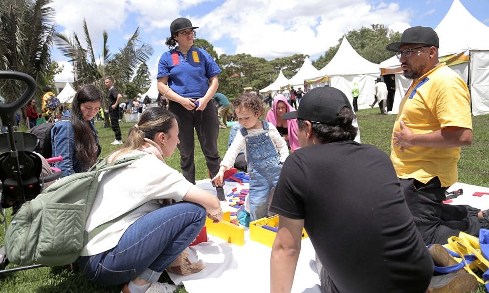 una niña juega con unos bloques de madrea mientras tres adultos la miran