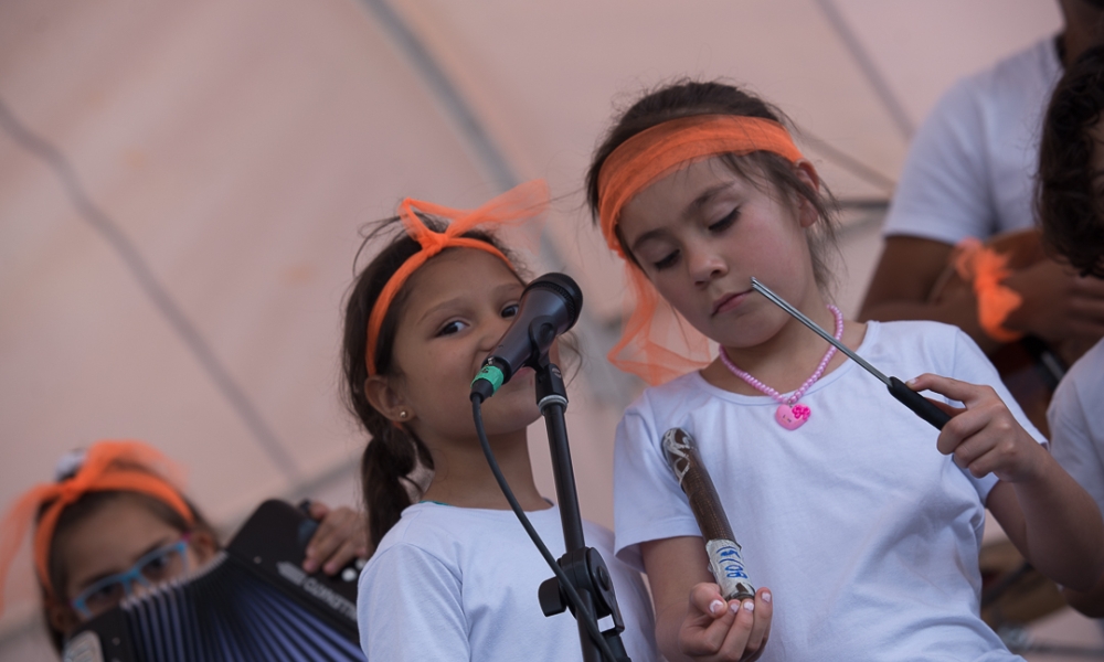 Niñas del crea Niñas con listón naranja en la cabeza, durante presentación artística