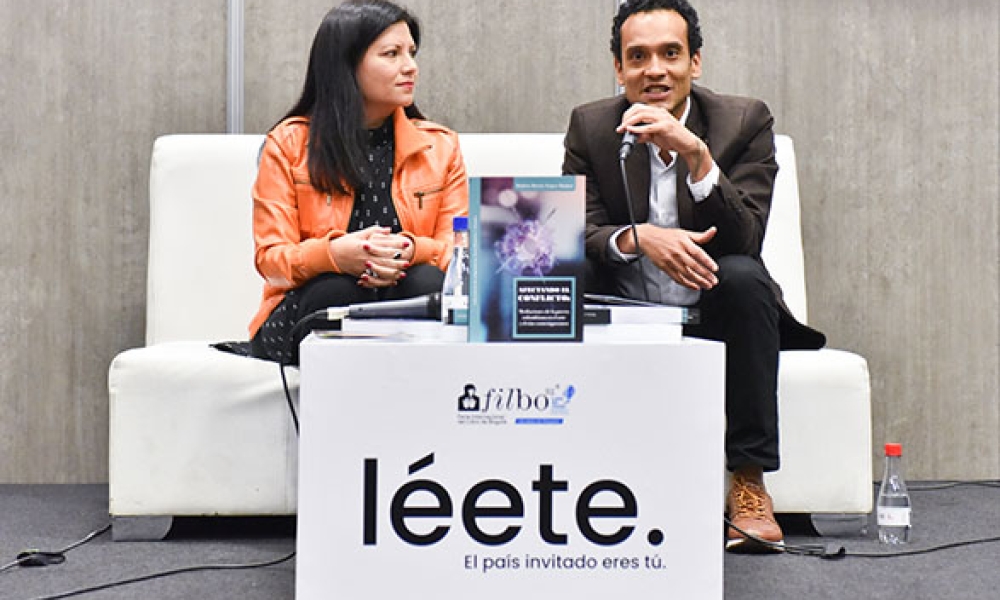 Rubén Yepes Dos personas exponen un libro