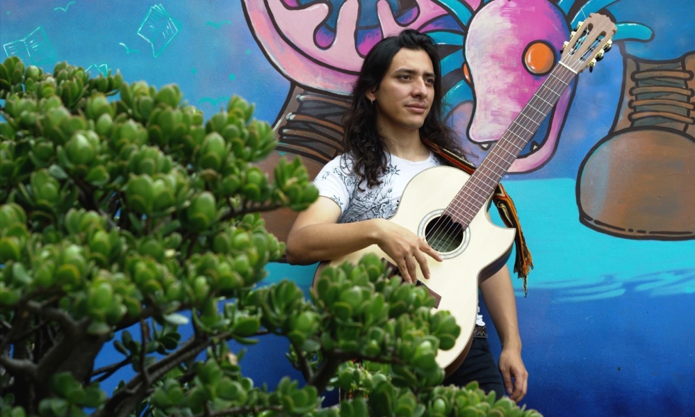 Jorge Juglares: un canto a Bogotá Hombre con guitarra entre arbustos