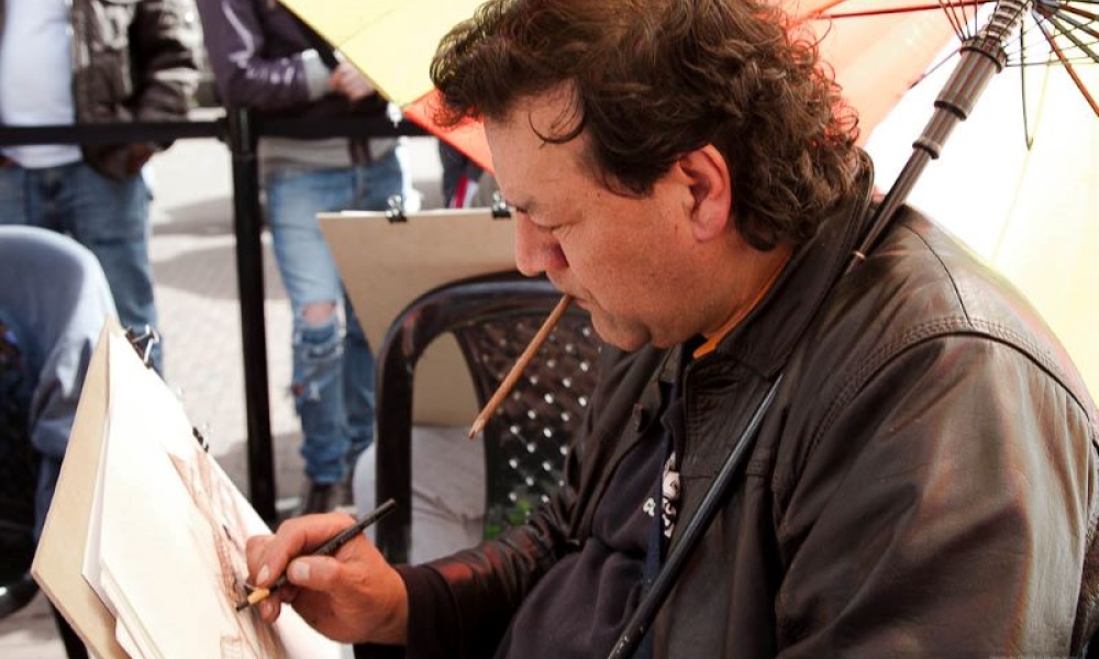 Fotografía: Claudia Palacios. Hombre dibuja con carboncillo sobre lienzo.