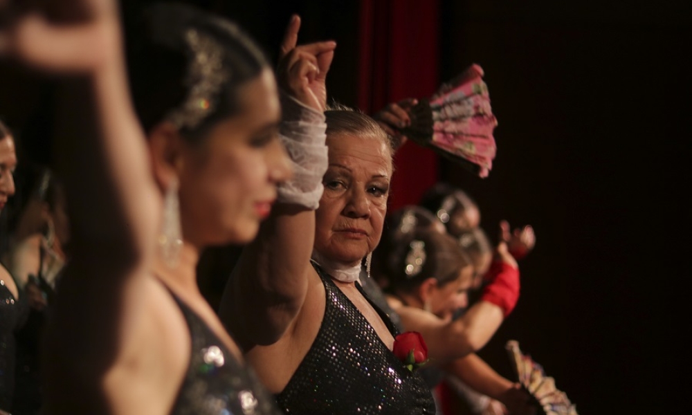 Mujer adulta mayor bailando en escenario. 