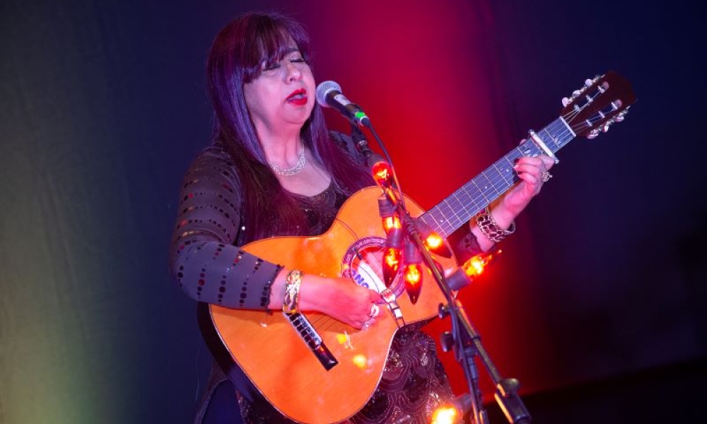 Fotografía: Juan Santacruz. 2021. Mujer cantando en el escenario con guitarra en mano