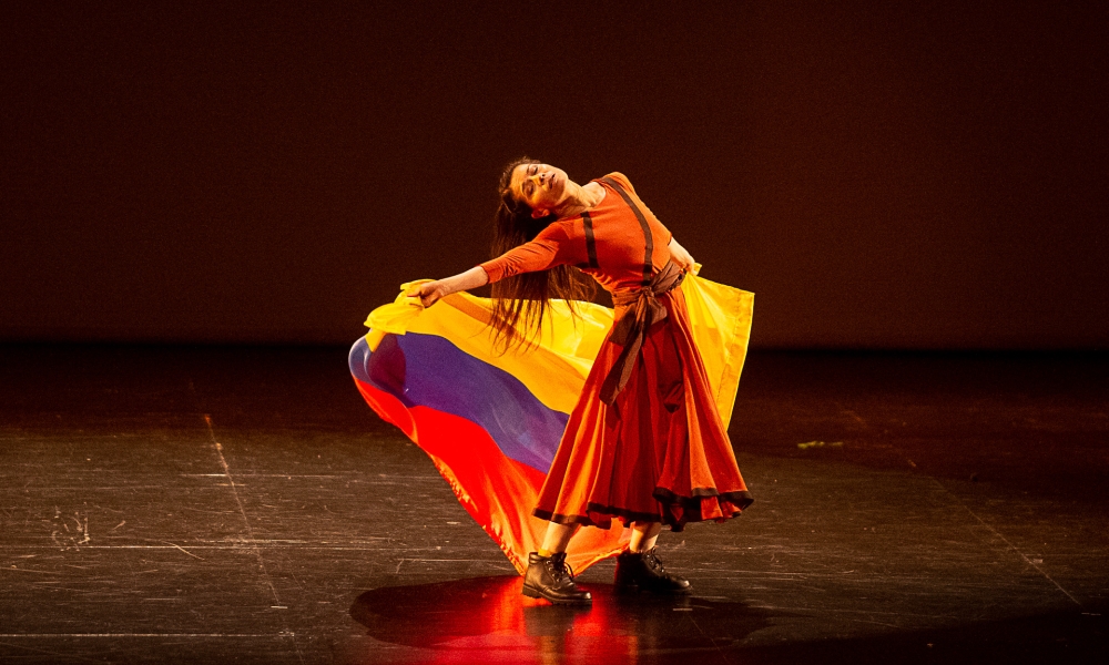 Bailarina con bandera de Colombia en un escenario. Bailarina con bandera de Colombia en un escenario.