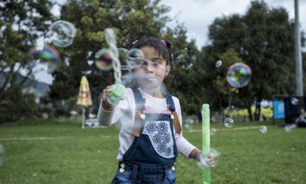 Recomendaciones Colombia al Parque Niña jugando al aire libre con bombas de jabòn