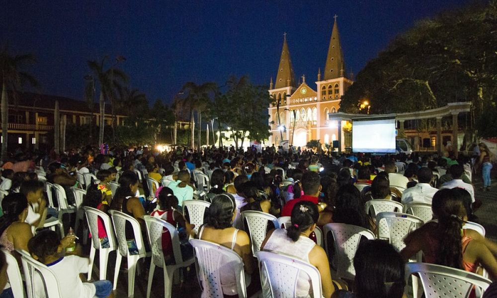Cine en lo barrios - FICCI personas sentadas en un parque viendo cine