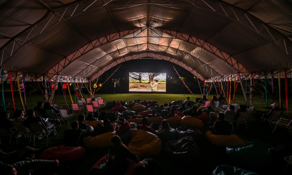 Cinemateca al Parque Personas sentadas en un parque viendo cine