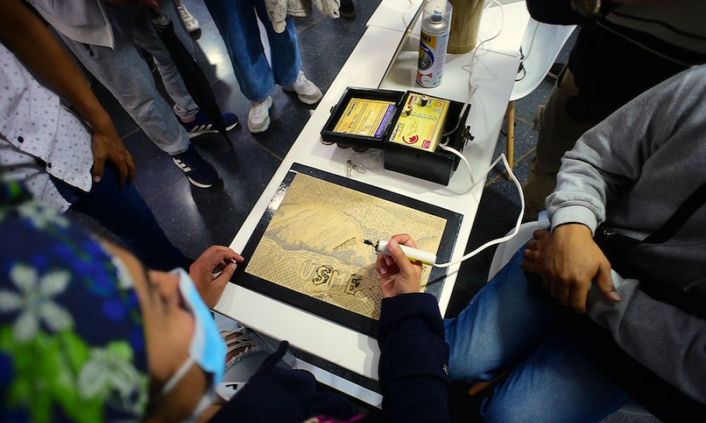 Integrantes de Fuego Joven realizando pirograbado sobre una tabla de madera. 