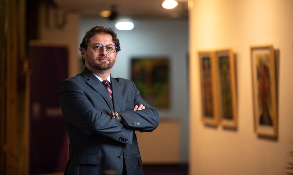Carlos Mauricio Galeano con galería de fondo a media luz. 