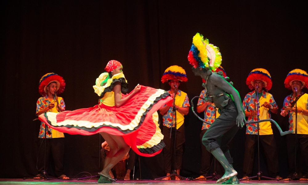 Dos bailarines en tarima con músicos de fondo 