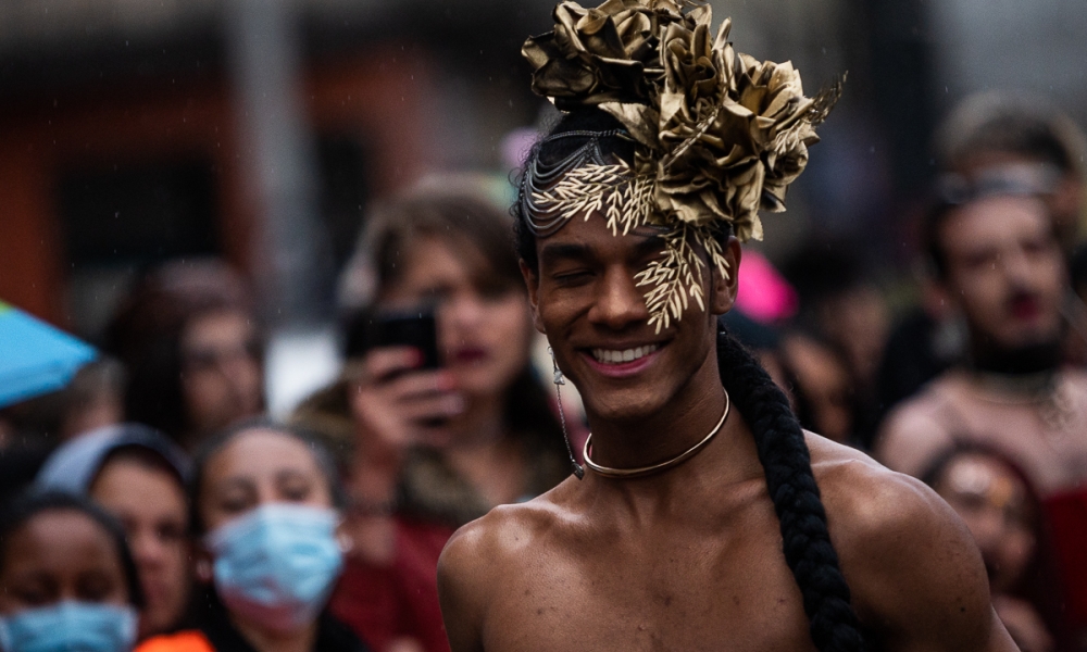 El Día de la Memoria Trans se conmemorará el 20 de diciembre en El Castillo de las Artes. Artista trans con un tocado dorado hace voguing en las afueras del Castillo de las Artes, de día.