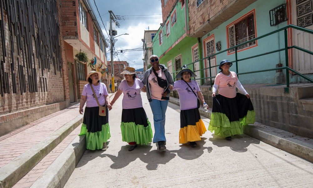 Los recorridos barriales fueron parte de la programación de la segunda edición del Festival Ciudad Deseo. Cinco mujeres caminando por una calle de Ciudad Bolívar de día.