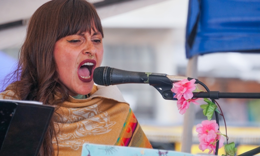 La artista Luisa Luna se presentará en el Festival Mujeres Arte y Memoria este 25N. Mujer canta frente a un micrófono de día
