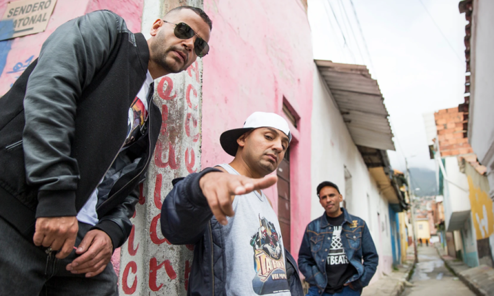 La Etnnia se presentará en el Concierto Somos Memoria este jueves 17 de noviembre. Tres artistas posan en una calle de día