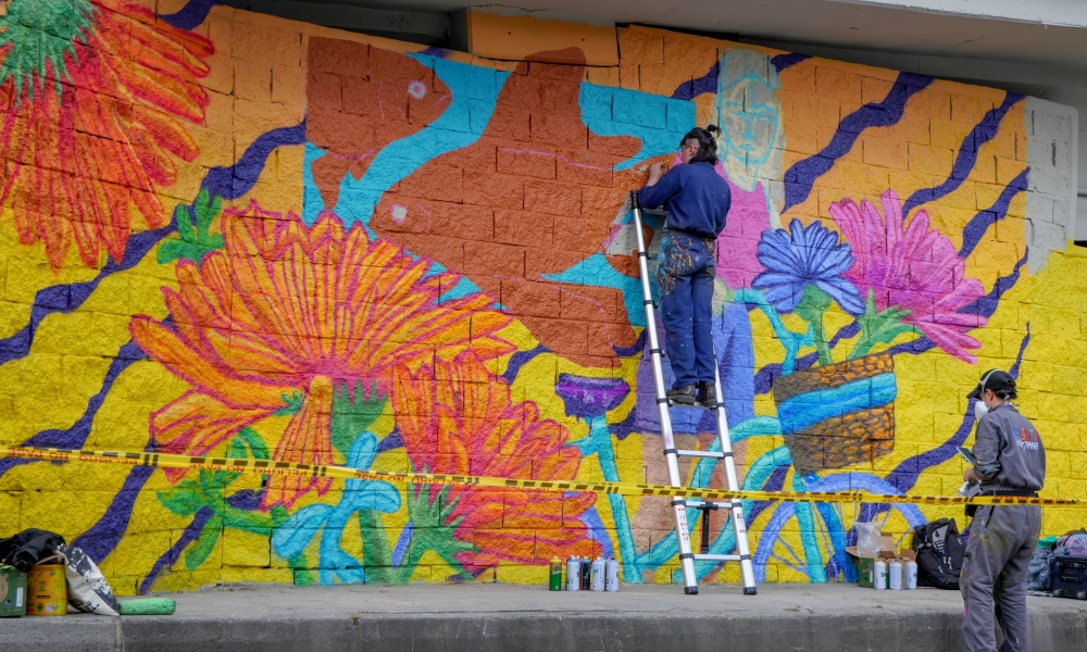El costado de una zona bajo puente siendo intervenido por un par de artistas