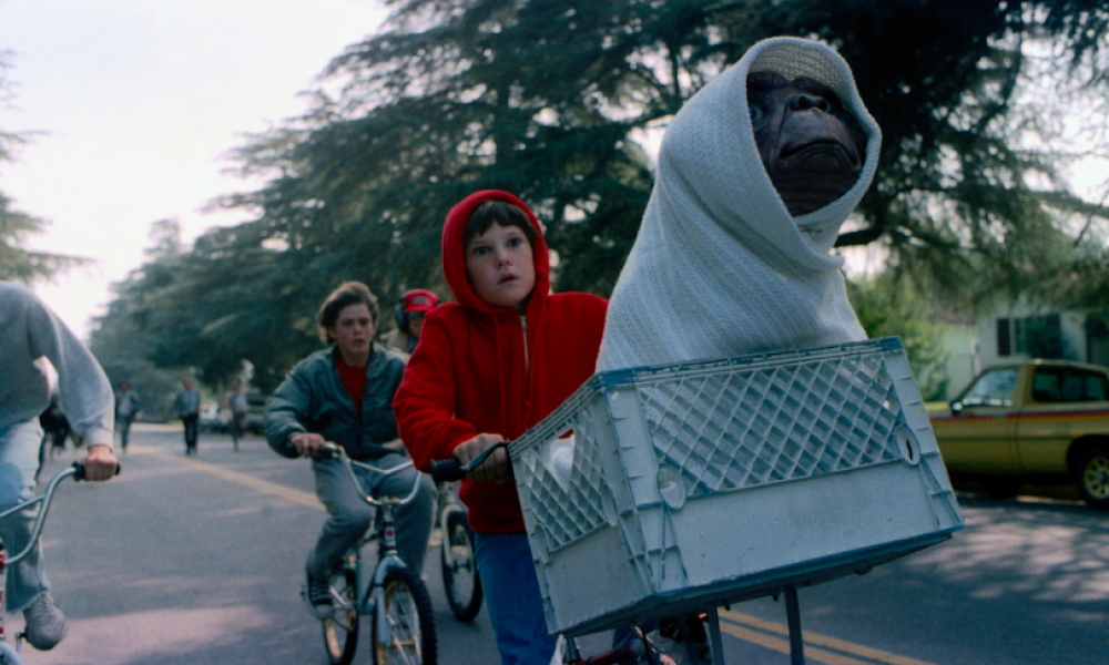 Película E.T. El extraterrestre. Dos jóvenes en bicicleta con un extraterrestre en la canastilla