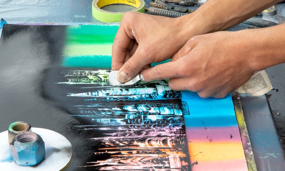 Manos de artista con espátula sobre obra de arte de día. 